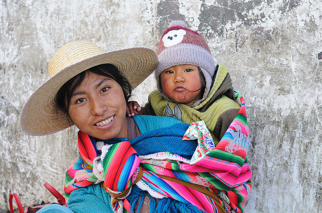 a mother carrying her child at the back with the use of a blanket