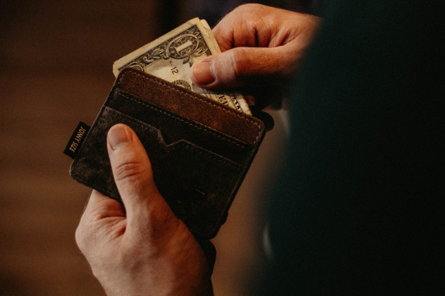 a man pulling a dollar from his wallter
