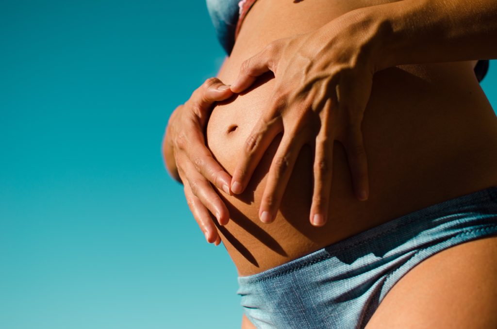 stretch marks - a woman holding her belly with her two hands
